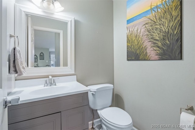 bathroom featuring toilet, baseboards, and vanity