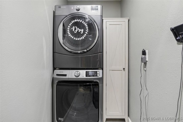 laundry area featuring stacked washer / dryer and cabinet space