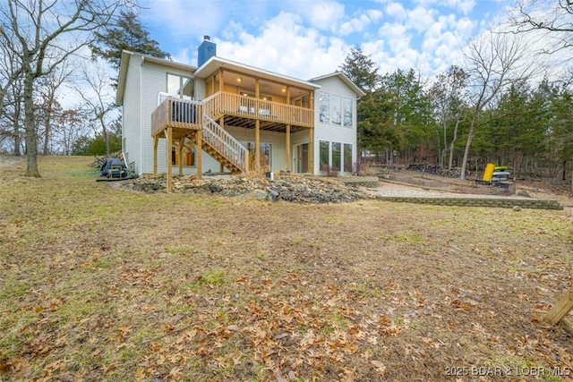 rear view of house featuring a deck, a chimney, stairs, and a lawn