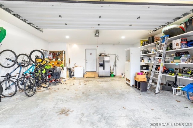 garage featuring bike storage, a garage door opener, and stainless steel fridge with ice dispenser