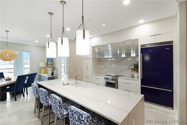 kitchen with hanging light fixtures, a center island with sink, a sink, and high quality appliances