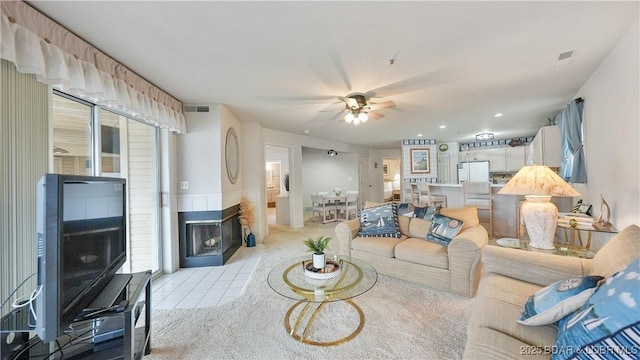 living area featuring a ceiling fan, visible vents, a multi sided fireplace, and light tile patterned floors