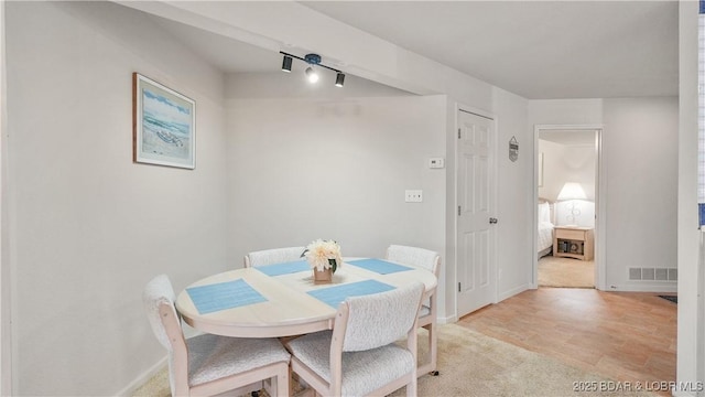 dining area with light colored carpet, visible vents, and baseboards