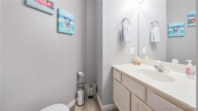 bathroom with baseboards, wood finished floors, and vanity