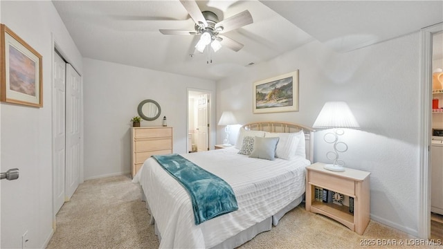 bedroom with baseboards, a closet, ensuite bath, and light colored carpet