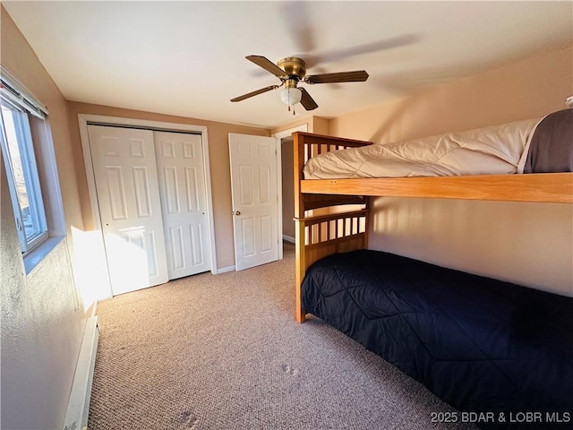 bedroom with carpet floors, ceiling fan, a baseboard heating unit, and a closet