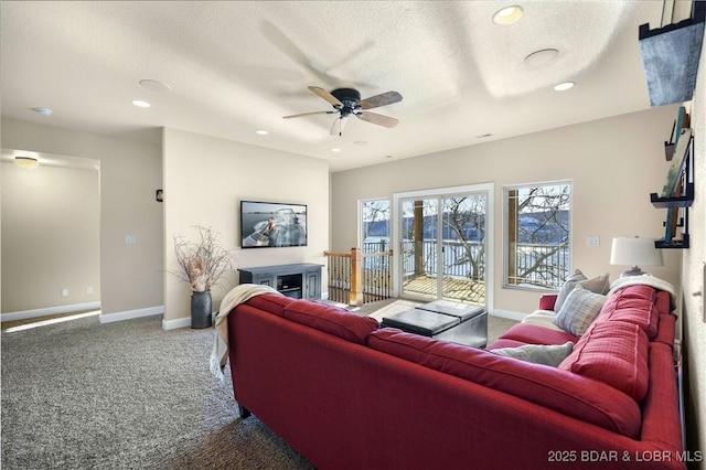 living room featuring carpet, ceiling fan, a textured ceiling, and baseboards