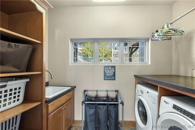 clothes washing area with a healthy amount of sunlight, cabinet space, a sink, and washing machine and clothes dryer