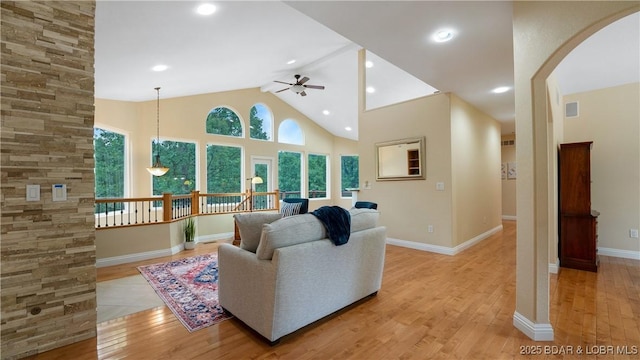 living room with light wood-type flooring, high vaulted ceiling, and a wealth of natural light