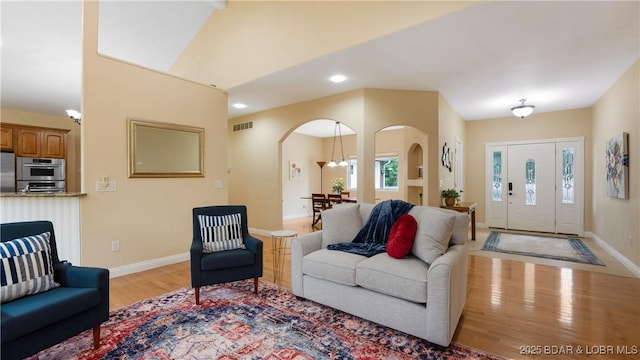 living room featuring light wood finished floors, baseboards, visible vents, arched walkways, and recessed lighting