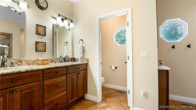 full bathroom featuring double vanity, a wealth of natural light, a sink, and toilet