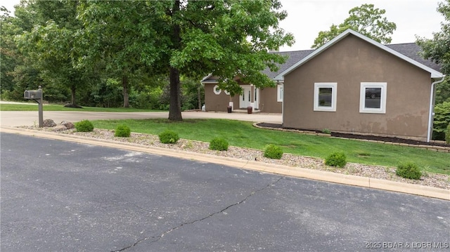 view of side of home featuring a lawn and stucco siding