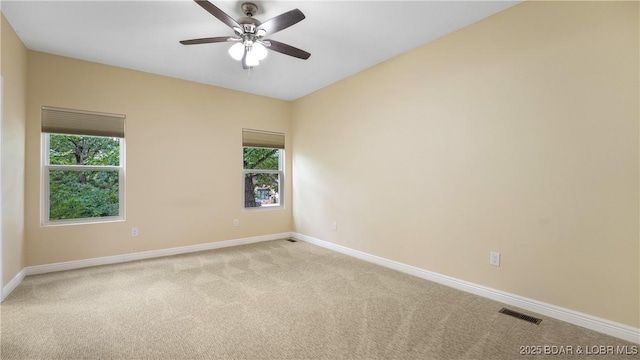 empty room featuring baseboards, visible vents, ceiling fan, and light colored carpet