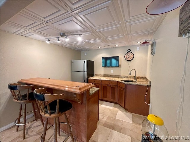 bar with baseboards, an ornate ceiling, freestanding refrigerator, wet bar, and a sink