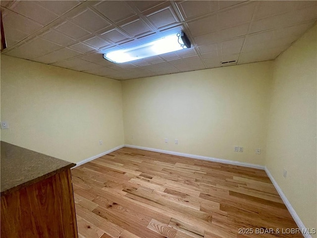 finished basement featuring baseboards, visible vents, and light wood-style floors