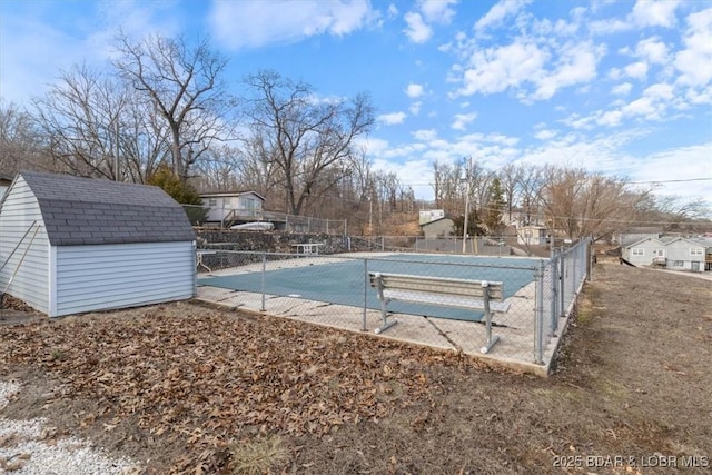 view of pool with a shed, fence, and an outbuilding