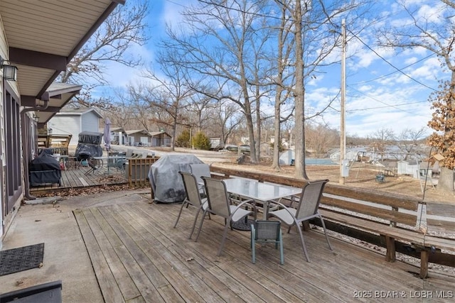 wooden deck featuring outdoor dining space, grilling area, and a residential view