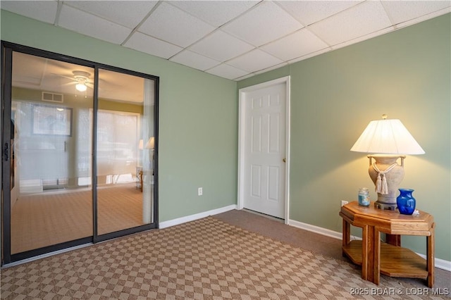 interior space featuring carpet floors, baseboards, visible vents, and a drop ceiling