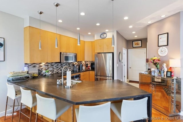 kitchen with a peninsula, appliances with stainless steel finishes, dark countertops, and pendant lighting