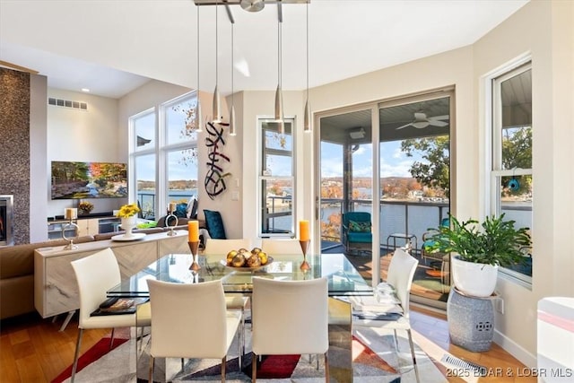 dining area with visible vents, a water view, baseboards, and wood finished floors