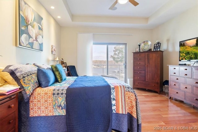 bedroom with recessed lighting, a raised ceiling, light wood-style floors, a ceiling fan, and access to outside