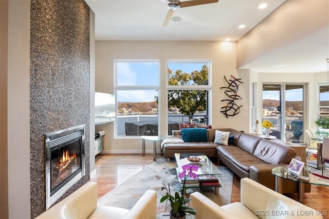 living area featuring ceiling fan, recessed lighting, a fireplace, baseboards, and light wood-style floors