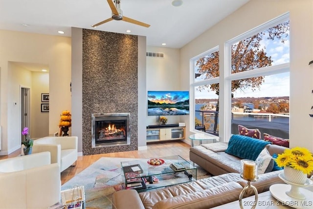 living area with recessed lighting, a ceiling fan, visible vents, light wood finished floors, and a tiled fireplace