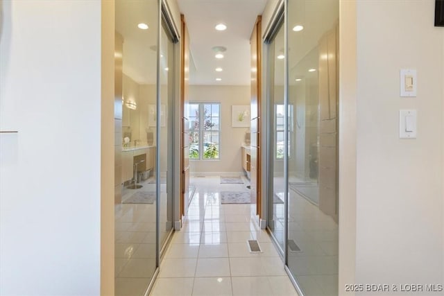 corridor with light tile patterned floors, recessed lighting, visible vents, and baseboards