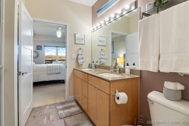 bathroom featuring toilet, a sink, ensuite bath, and double vanity