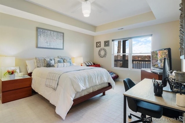 bedroom with ceiling fan, a tray ceiling, and baseboards