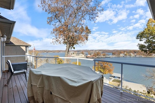 wooden deck featuring a water view and a grill