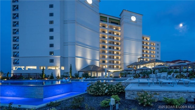 property at night featuring a community pool