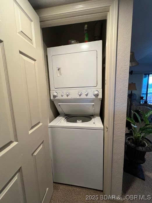 clothes washing area featuring stacked washer and dryer and laundry area