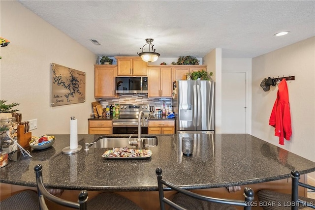 kitchen featuring tasteful backsplash, visible vents, appliances with stainless steel finishes, a breakfast bar area, and a sink