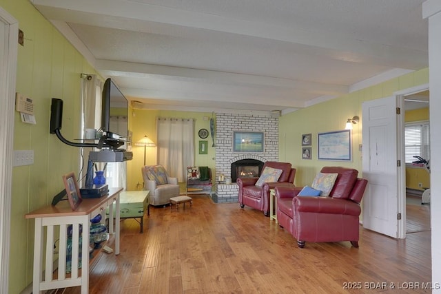 sitting room with light wood-style floors, beam ceiling, and a fireplace