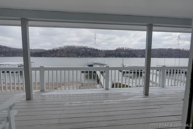 dock area with a wooded view and a deck with water view