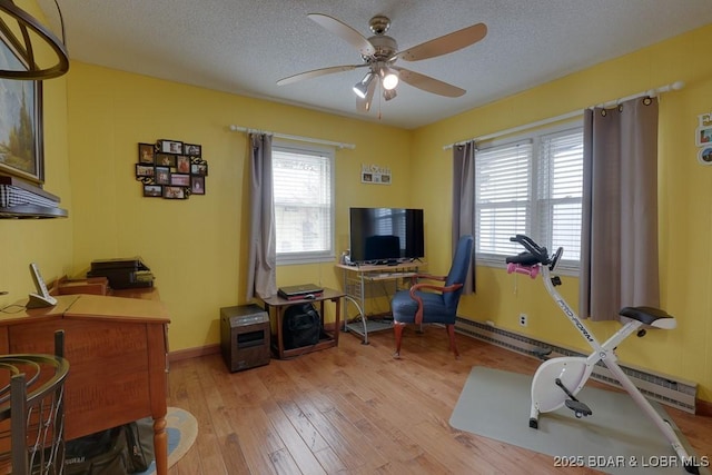 interior space featuring light wood-style floors, ceiling fan, baseboards, and a textured ceiling