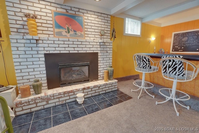 living area with beam ceiling, a fireplace, wooden walls, a bar, and dark tile patterned floors