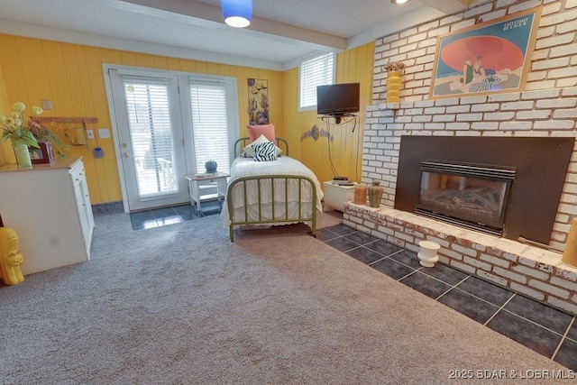 bedroom featuring access to exterior, beam ceiling, a fireplace, dark carpet, and dark tile patterned flooring