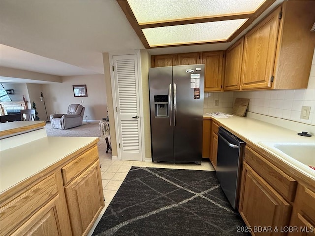 kitchen featuring light tile patterned floors, tasteful backsplash, brown cabinetry, stainless steel appliances, and light countertops