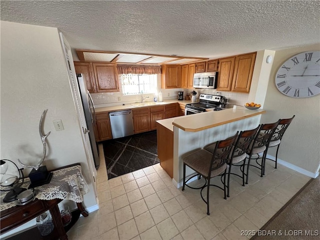 85 La Jolla Dr Unit 352-2A, Lake Ozark, MO 65049 - kitchen with stainless steel appliances, a peninsula, a kitchen bar, light countertops, and a textured ceiling