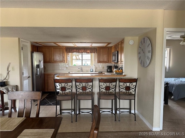 85 La Jolla Dr Unit 352-2A, Lake Ozark, MO 65049 - kitchen featuring stainless steel fridge with ice dispenser, a sink, a peninsula, light countertops, and a breakfast bar area