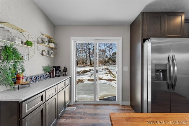 kitchen with light countertops, dark brown cabinetry, stainless steel fridge with ice dispenser, and open shelves