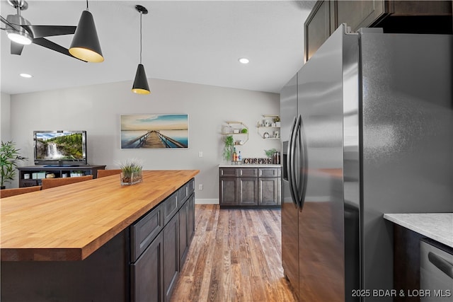 kitchen with butcher block counters, wood finished floors, appliances with stainless steel finishes, a center island, and decorative light fixtures