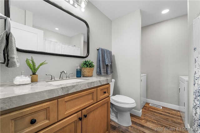 full bathroom with baseboards, visible vents, toilet, wood finished floors, and vanity