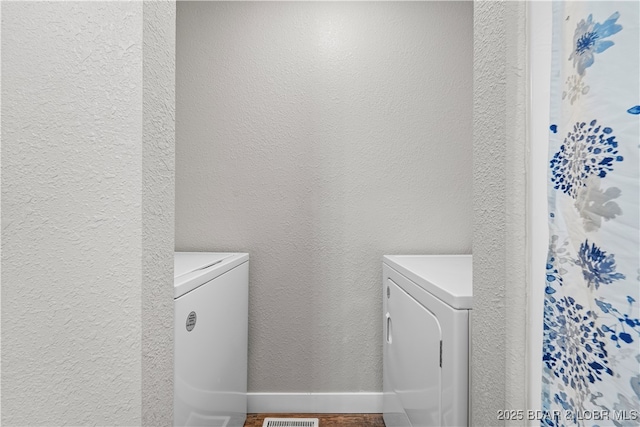 laundry room featuring washer and dryer, laundry area, a textured wall, and baseboards