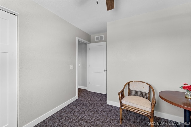 sitting room with visible vents, dark carpet, baseboards, and ceiling fan