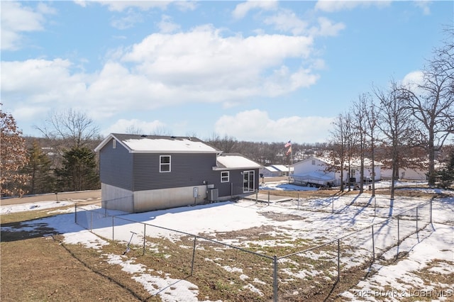 snow covered rear of property featuring central air condition unit and fence