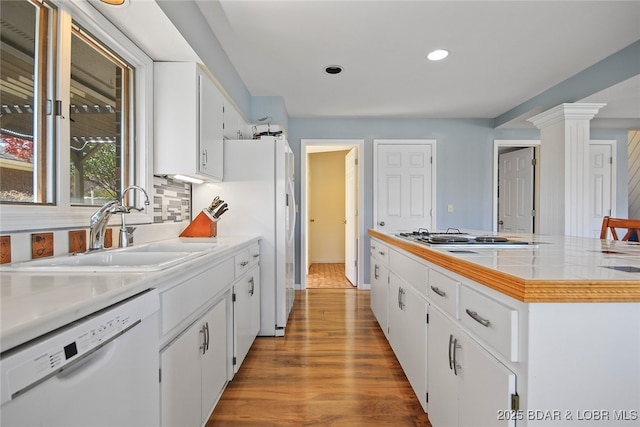 kitchen with white appliances, a sink, white cabinetry, light countertops, and tasteful backsplash