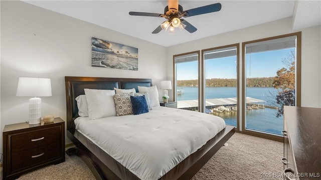 bedroom with a water view, access to exterior, ceiling fan, and light carpet